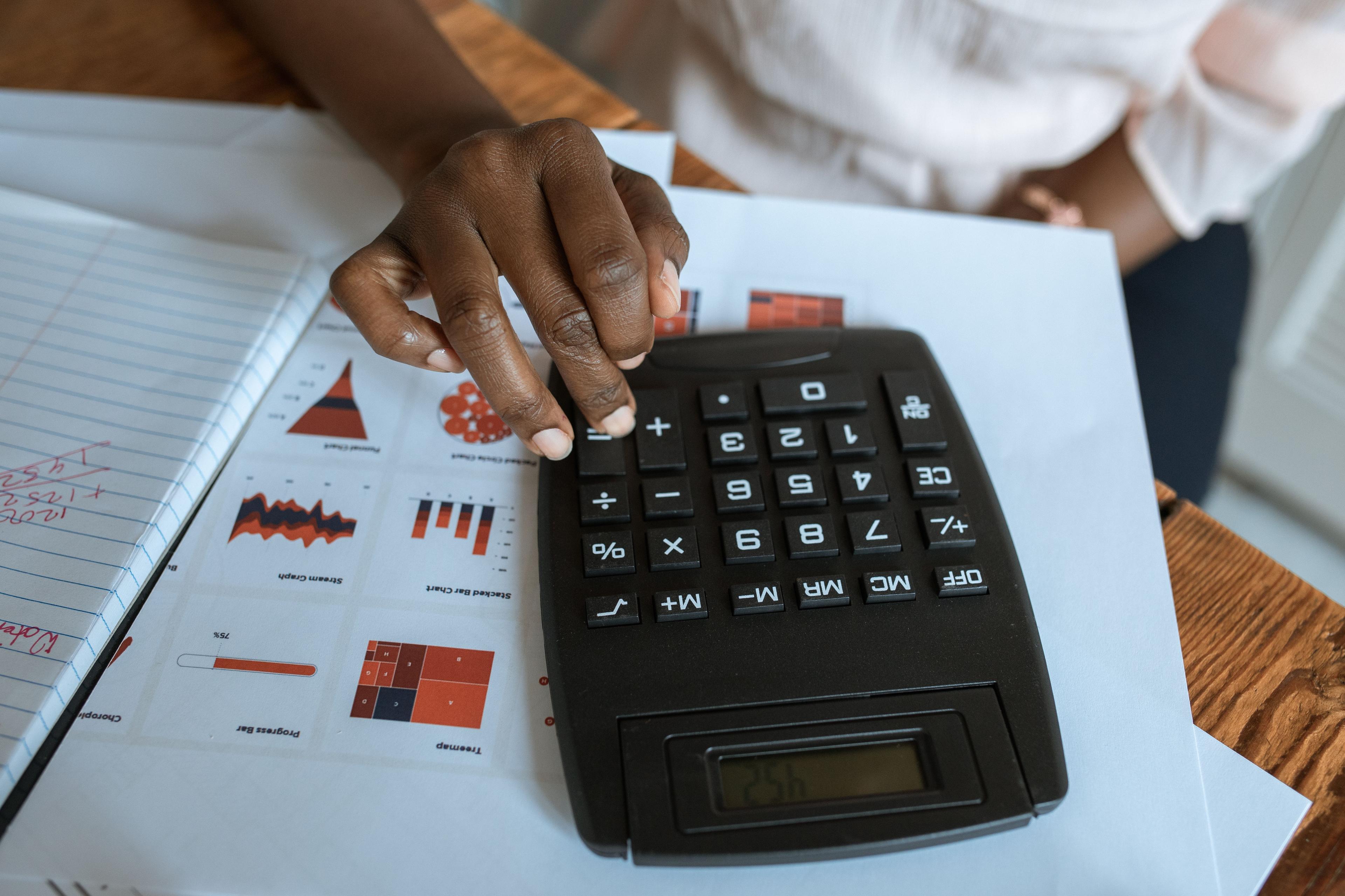 Persona usando calculadora sobre documentos financieros